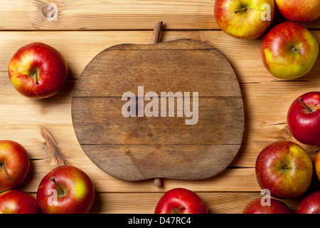 Frische Äpfel auf Holztisch. Komposition mit Obst und Schneidebrett mit Apfel-Form. Textfreiraum Stockfoto