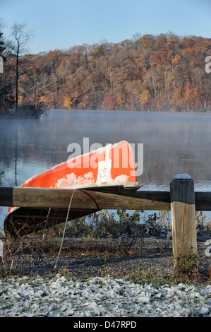 Kanu fahren Sie auf einem verschneiten einen nebligen See in der freien Natur, kalten Morgen Sonnenschein, Herbst Gebirgshintergrund. Stockfoto