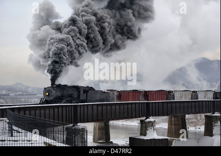 Brücke über den Potomac River machen große Rauchfahne in der kalten Luft, eine alte Lokomotive mit Vintage Güterzug Dampflok. Stockfoto