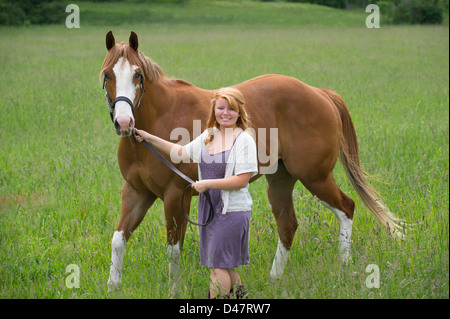 Junge Frau Pferd durch Wiese, eine 18 Jahre alte rote behaarte Reiterin führt. Stockfoto