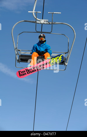 Snowboarder Reiten Winter Skilift genommen von unten mit bunten rosa Board mit lustigen Satz. Stockfoto