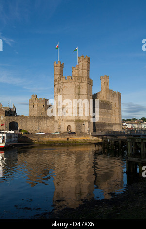 Ein Spiegelbild im Wasser von Caernarfon Castle in Wales mit ihren Mauern, Türmen und Zinnen. Stockfoto