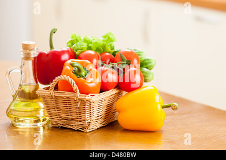 Gesundes Essen frisches Gemüse im Korb und eine Flasche mit Öl auf dem Küchentisch Stockfoto