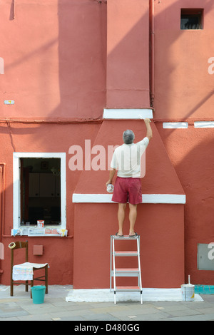 Mann malen bunte Häuser auf der Insel Burano in der Nähe von Venedig, Italien Stockfoto