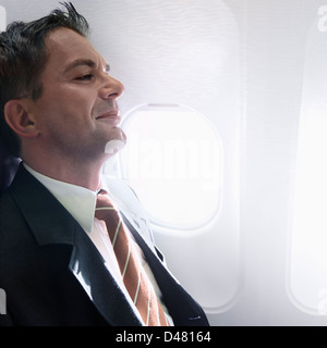 Ein Geschäftsmann, ein Flugzeug mit einem Grinsen auf seinem Gesicht, wie jemand mit angenehmen Gedanken unterwegs oder planen eine Überraschung. Stockfoto