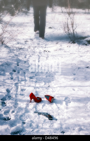 rote high Heels und einer Pistole im Schnee, ist ein Mann Fuß entfernt Stockfoto