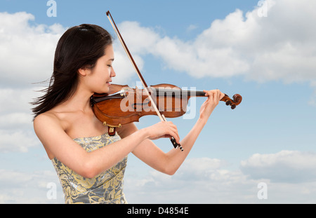 junge asiatische Frau, die im Freien, mit dem Geigenspiel Wolken Hintergrund Stockfoto