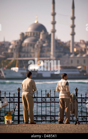 Türkische Männer Angeln in das Goldene Horn von Istanbul. Im Hintergrund über das Wasser ist die Yeni-Moschee Stockfoto