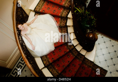 Braut auf verzierten Treppe mit voll mit Röckchen Creme trägerlosen Brautkleid von oben fotografiert Stockfoto