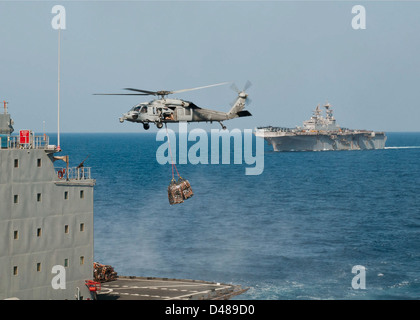 Ein MH-60 s führt Lieferungen für USS Iwo Jima. Stockfoto