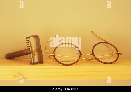 Augenhöhe Blick auf schmalen Holzregal mit angeschlagenen gestochen und Vintage Runde Brille mit Draht-Griffe Stockfoto