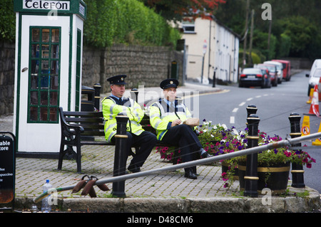 Zwei irische Gardai sitzt auf einer Parkbank in dem malerischen Dorf Enniskerry in Wicklow Irland Stockfoto