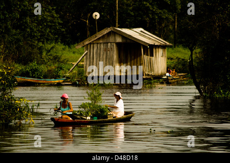 schwimmende Häuser und Menschen Rudern in kleinen Kanus in der Nähe von Manaus Stadt, Bundesstaat Amazonas, Nord-Brasilien. Stockfoto