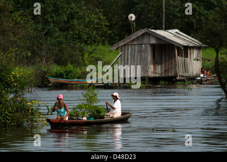 schwimmende Häuser und Menschen Rudern in kleinen Kanus in der Nähe von Manaus Stadt, Bundesstaat Amazonas, Nord-Brasilien. Stockfoto