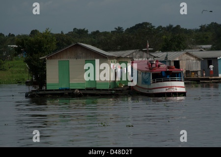 schwimmende Häuser und Menschen Rudern in kleinen Kanus in der Nähe von Manaus Stadt, Bundesstaat Amazonas, Nord-Brasilien. Stockfoto