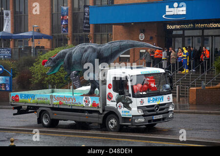Bournemouth, UK 8. März 2013. Komödie Darren der Dinosaurier ist auf den Straßen von Bournemouth zugunsten von Comic Relief veröffentlicht. Darren, die Dinosaurier ist drei Meter hoch durch acht Meter lang und in Walking with Dinosaurs verwendet wurde, wurde er von prominenten Chris Jarvis von außerhalb der BIC freigelassen. Die Veranstaltung wurde organisiert von Sainsburys Menschen zu ermutigen, rufen Sie in jedem Geschäft zu bekommen ihre roten Nasen, sich zu schützen, sollten sie die prähistorische Kreatur unterwegs sehen. Stockfoto