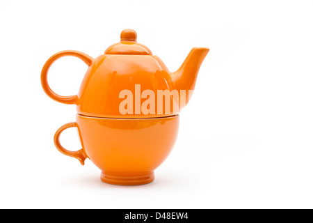 Teaset. Single orange Teekanne und Tasse auf einem weißen Hintergrund. Teekanne konzipiert auf der Schale sitzen. Stockfoto