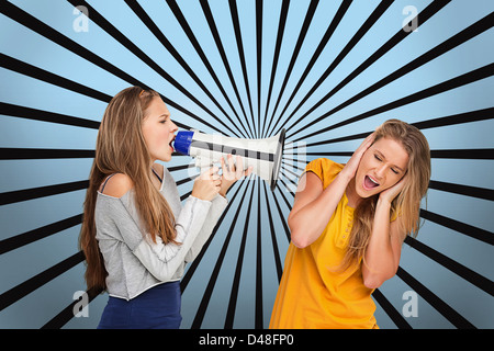 Mädchen an einem anderen durch Megaphon schreien, während sie ihre Ohren bedeckt Stockfoto