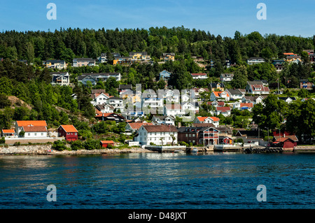 Eine kleine Stadt an den Ufern des Oslofjord mit unberührten weißen Häusern unter Tannen in der späten Nachmittagssonne schauen Stockfoto