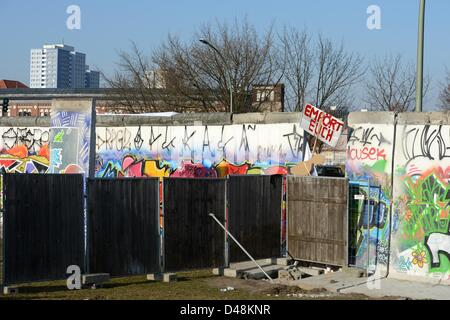 Ein Holzzaun teilt den öffentlichen Bereich von der Baustelle von Luxus-Appartements (hinter dem Zaun) auf der Westseite der East Side Gallery in Berlin, Deutschland, 7. März 2013. Das Zeichen "entsetzt sein" markiert die Stelle, wo ein Teil der Wand werden, um eine Öffnung zu schaffen entfernt soll. Proteste verhindert den Plan, nachdem Teile der Mauer bereits entfernt worden war. Foto: Jens Kalaene Stockfoto