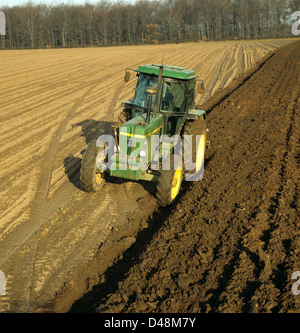 Einen alten John Deere Traktor ein Feld pflügen, im Winter im Abendlicht mit niedrigen Schatten Stockfoto