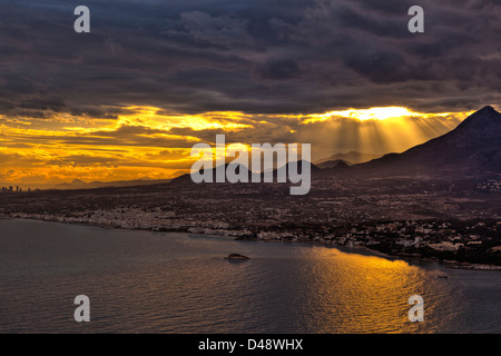 Altea Bucht bei Sonnenuntergang, mit der Sonne durch die Wolken und Berge, Altea, Provinz Alicante, Costa Blanca, Spanien Stockfoto