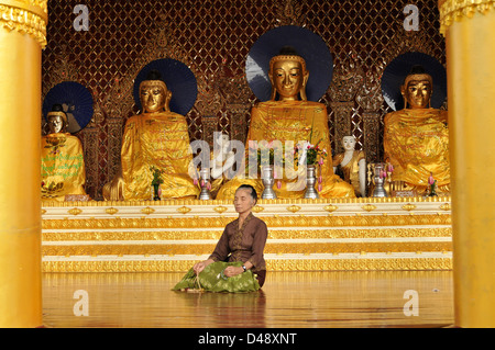 Meditieren ältere Frau vor Buddha-Statuen, Shwedagon-Pagode, Yangon, Myanmar Stockfoto