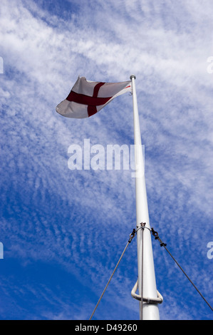 Englische Flagge von St. George an Spitze der Fahnenstange gegen blauen Himmel fliegen Stockfoto