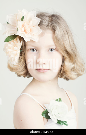 Engelhaften blond kaukasische Mädchen mit rosa Blumen in ihrem Haar, direkt in die Kamera schauen. Stockfoto