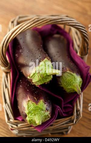 Rohe Auberginen oder Auberginen im Korb auf hölzernen Backround. Stockfoto