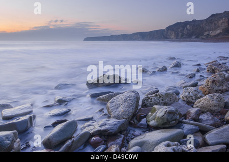 Morgen Flut an einem steinigen Strand vor Sonnenaufgang Stockfoto