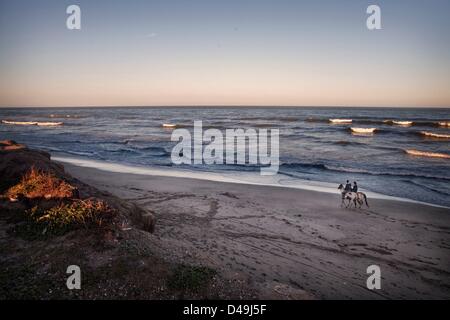9. März 2013 - Mar Del Plata, Buenos Aires, Argentinien - ein junges Paar Reiten am Strand bei Sonnenuntergang. Pferde und die Landschaft sind fester Bestandteil des argentinischen Lebens und können an vielen Orten wie der Strand und die öffentlichen Parks stundenweise gemietet werden. (Bild Kredit: Ryan Noble/ZUMAPRESS.com ©) Stockfoto