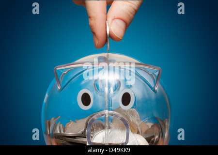 Speichern, männliche Hand, eine Münze ins Sparschwein. Stockfoto