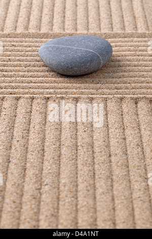 Ein Kieselstein auf einen geharkt Sand Zen-Garten auf der Suche an den Furchen. Stockfoto