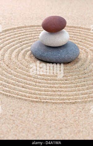 Drei Kieselsteine gestapelt auf einem kreisförmigen geharkt Zen-Garten Stockfoto