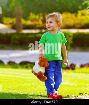 Foto von niedlichen kleinen Jungen in den Park Holding Teddybären, entzückenden Kind spielen mit Stofftier im Freien im Frühling, süßen Kleinkind Stockfoto