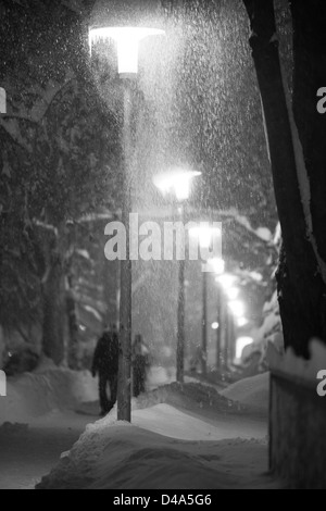 Schwere Schnee auf der Straße in der Nacht. Die Menschen sind zu Fuß unter Straßenlaternen während schneit. Extreme Wetterbedingungen. Schwarzweißbild. Stockfoto