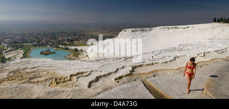 Panorama der Frau im roten Bikini auf weißer Travertin Calciumcarbonat mineralischen Terrassen an der Türkei Pamukkale heißen Quellen mit Blick auf Dorf Pamukkale Stockfoto