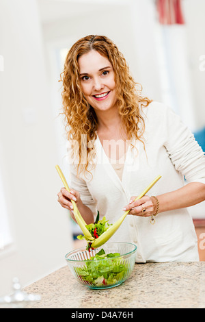 Porträt der glückliche Frau mischen Salat in die Küche zu Hause Stockfoto