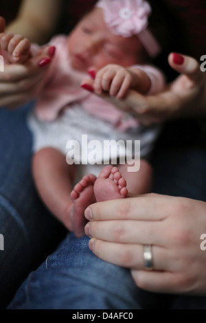 Ein kleines neugeborenes Baby Wabbel auf der Mutter Schoß, mit dem Ende des Babys Füße. Stockfoto