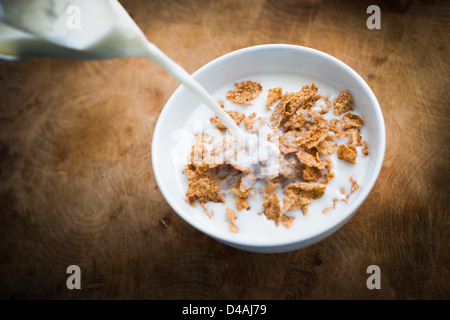 Milch über Bran Flakes Frühstückscerealien gegossen wird. Stockfoto