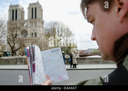 Ein Mann, Blick auf eine Karte vor der Notre Dame Kathedrale in Paris, Frankreich. Stockfoto