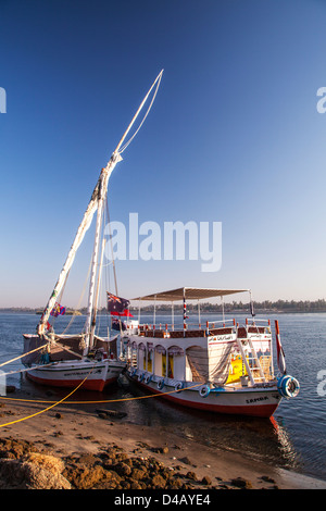 Felucca und Unterstützung Touristenboot vertäut am Ufer des Nils in der Nähe von Assuan bei Sonnenaufgang. Stockfoto