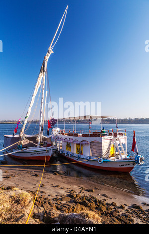 Felucca und Unterstützung Touristenboot vertäut am Ufer des Nils in der Nähe von Assuan bei Sonnenaufgang. Stockfoto