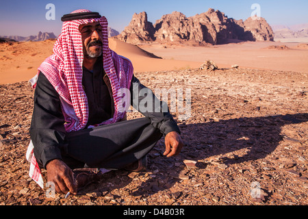 Ein Beduinen-Mann sitzt vor dem Hintergrund der jordanischen Wüste Wadi Rum oder Tal des Mondes Stockfoto