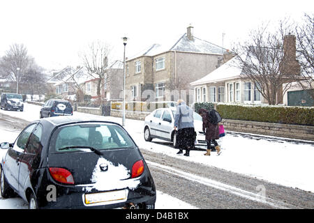 Edinburgh, Schottland. 11. März 2013. Willowbrae Bereich im schottischen Edinburgh leidet seine erste Schnee Störung des Winters, mit Blizzard Bedingungen manchmal. Eine Mutter bekommt ihre Kinder zur Schule mit Schlitten und der Hauptverkehrszeit-Bus-Warteschlangen zu verlängern, da der Datenverkehr sichert Stockfoto