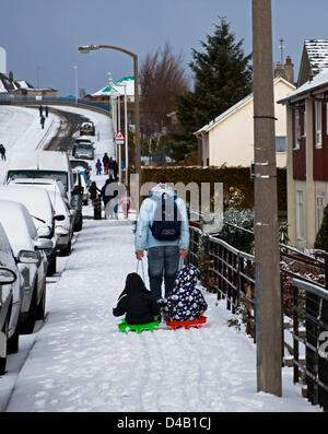 Edinburgh, Schottland. 11. März 2013. Willowbrae Bereich im schottischen Edinburgh leidet seine erste Störung der Schnee des Winters, eine Mutter bekommt ihre Kinder zur Schule mit Schlitten und der Hauptverkehrszeit-Bus-Warteschlangen zu verlängern, da der Datenverkehr sichert Stockfoto