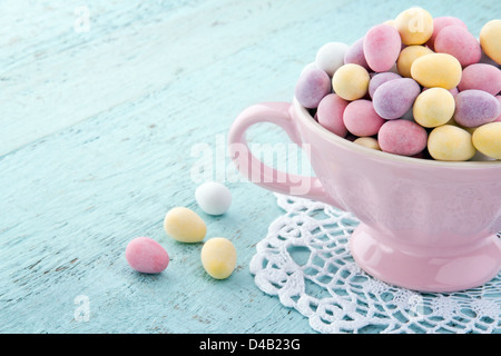 Kleinen Pastellfarben Ostereier in eine rosa Tasse auf Licht blau Holztisch mit Textfreiraum Stockfoto