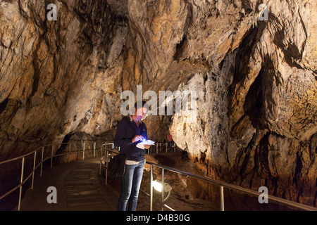 Frau, die gerade Karte mit Fackel in Nationalpark Aggtelek Höhlen in Ungarn, auch genannt Baradla-Domica Höhlen Stockfoto