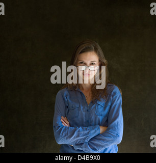 Zuversichtlich Geschäftsfrau oder Lehrer mit abgelegten Brille betrachten Sie auf dunkle Tafel Hintergrund Stockfoto